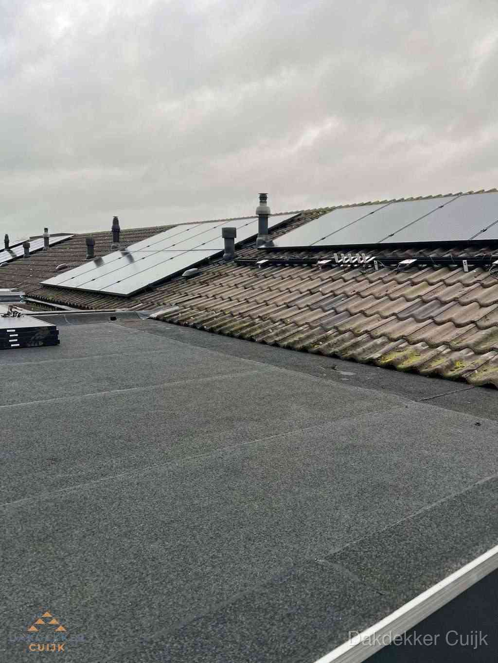 Plat dak inspectie met bitumen bedekking naast schuin pannendak in Cuijk