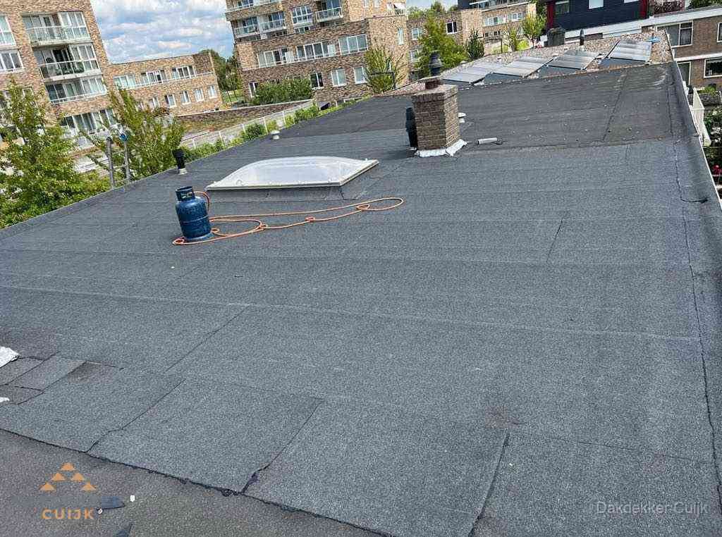 Bitumen dakbedekking op plat dak met lichtkoepel en schoorsteen in Cuijk