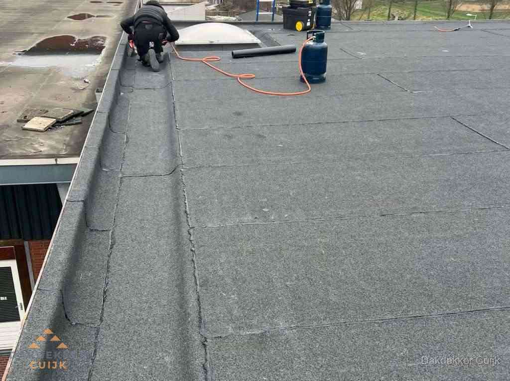 Dakdekker repareert bitumen dakbedekking op groot plat dak in Cuijk